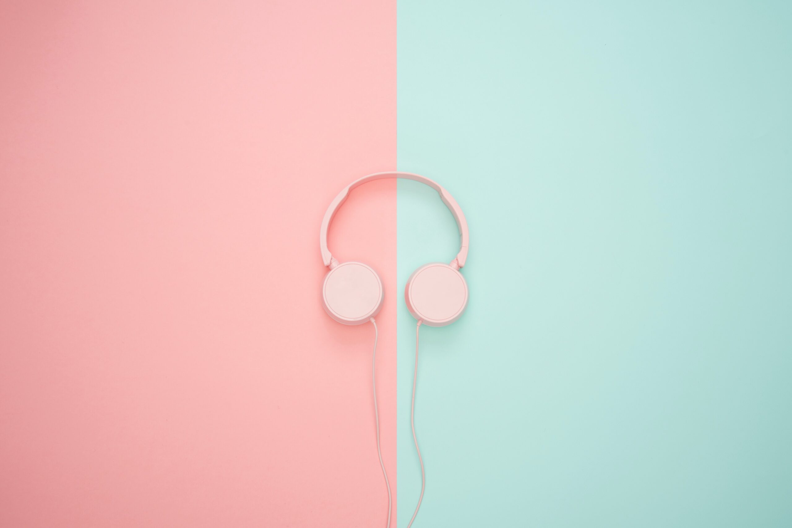 A pair of pink headphones lays on a half-pink half-blue floor