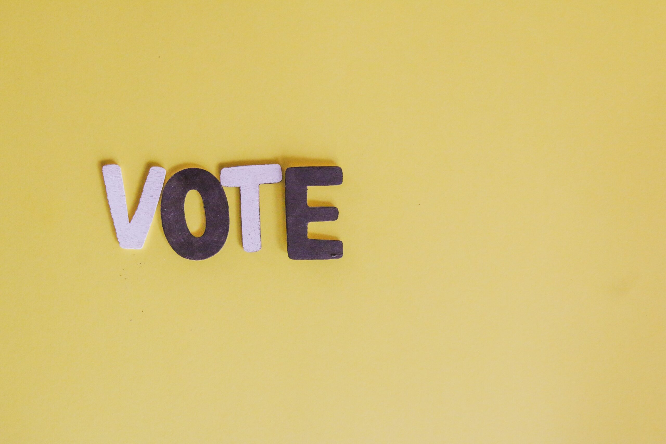 The word "vote" in brown and white letters on a yellow background