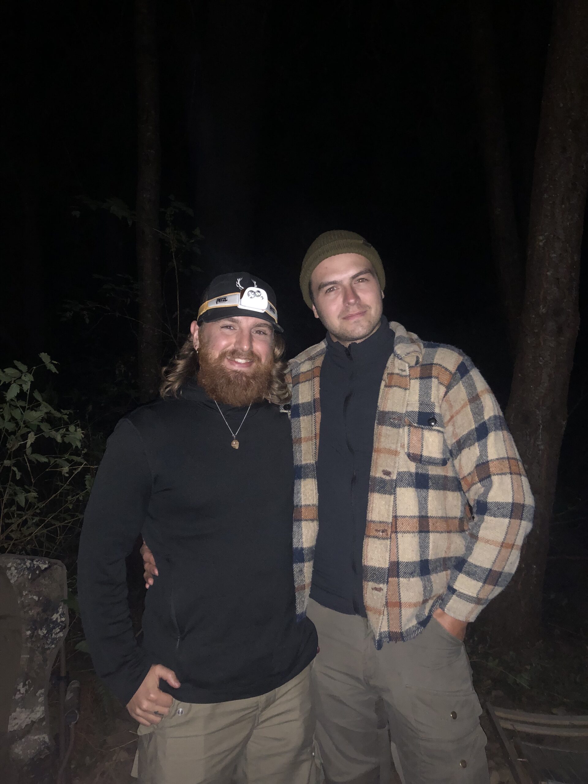 Two VIU students pose for a picture in a dark forest. They are waiting for the timer to go off so they can check the bird traps.