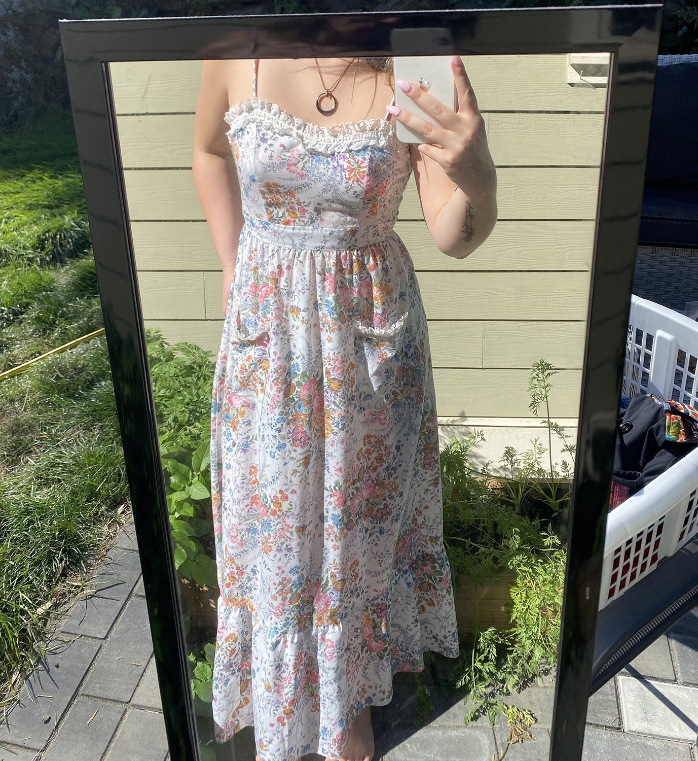 Mirror selfie taken outside featuring a floor-length floral patterned white and rosy dress.