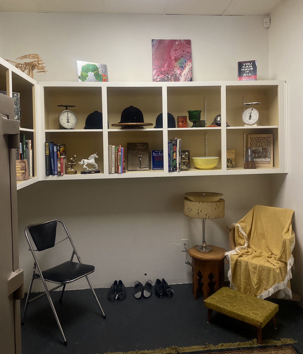Seating area with two chairs and a cubed wall shelf in a thrift shop.