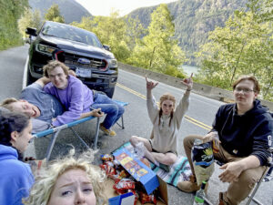 Group photo of Jenaya and friends sat between their vehicles at Cameron Lake.